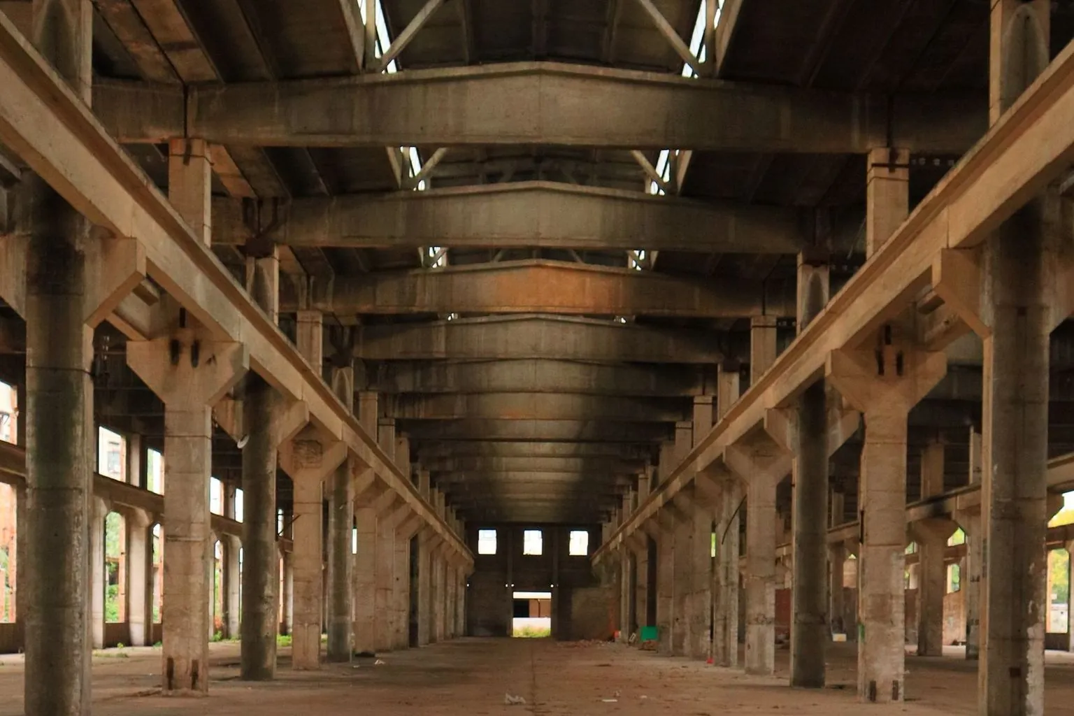 Leere Industriehalle – Gewerbe- und Betriebsauflösung Leere Industriehalle mit Reihen von Betonstützen und offener Bodenfläche